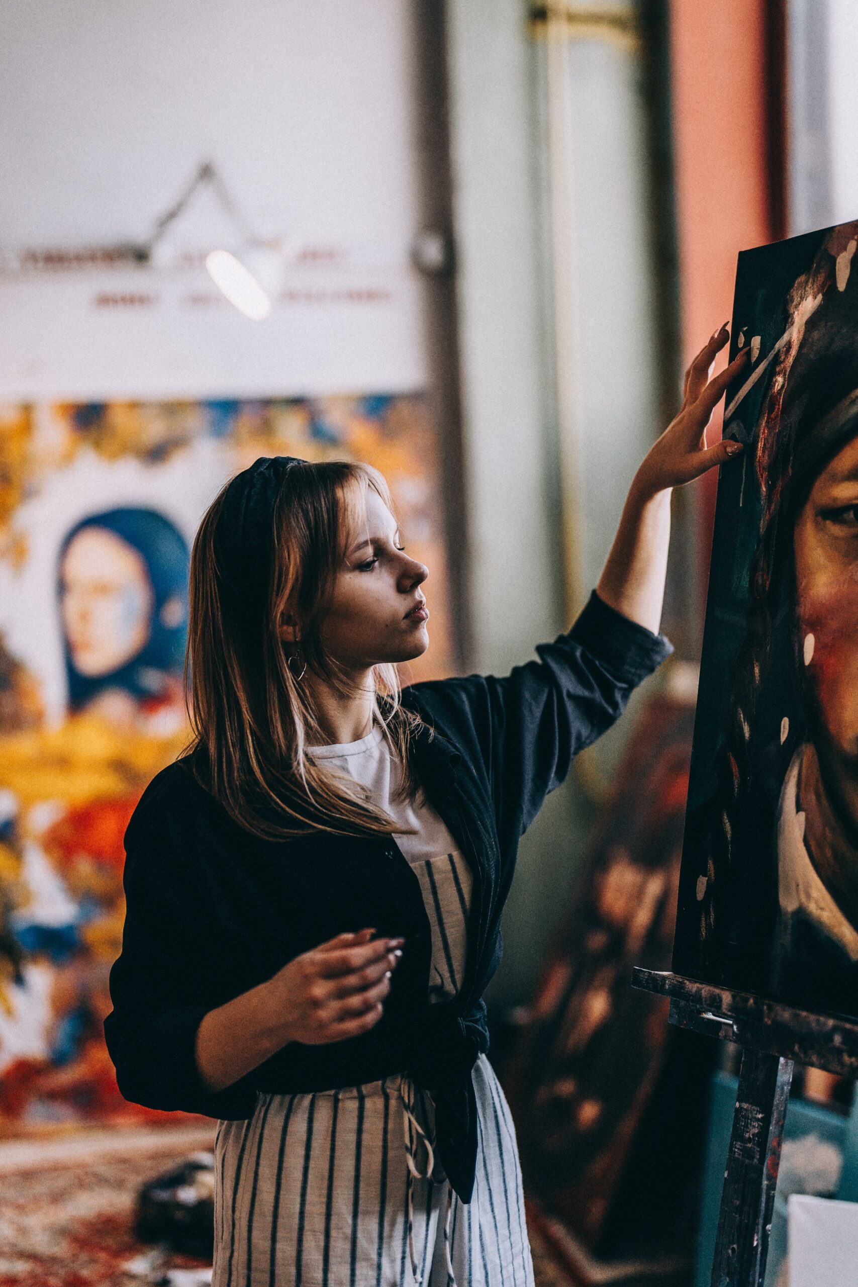 Woman artist in a studio painting on canvas, featuring a colorful and creative environment.